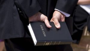 Hand Holding Bible behind back