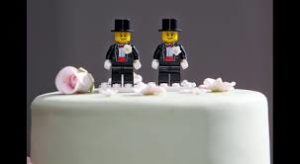 Two male lego figures on top of a wedding cake.